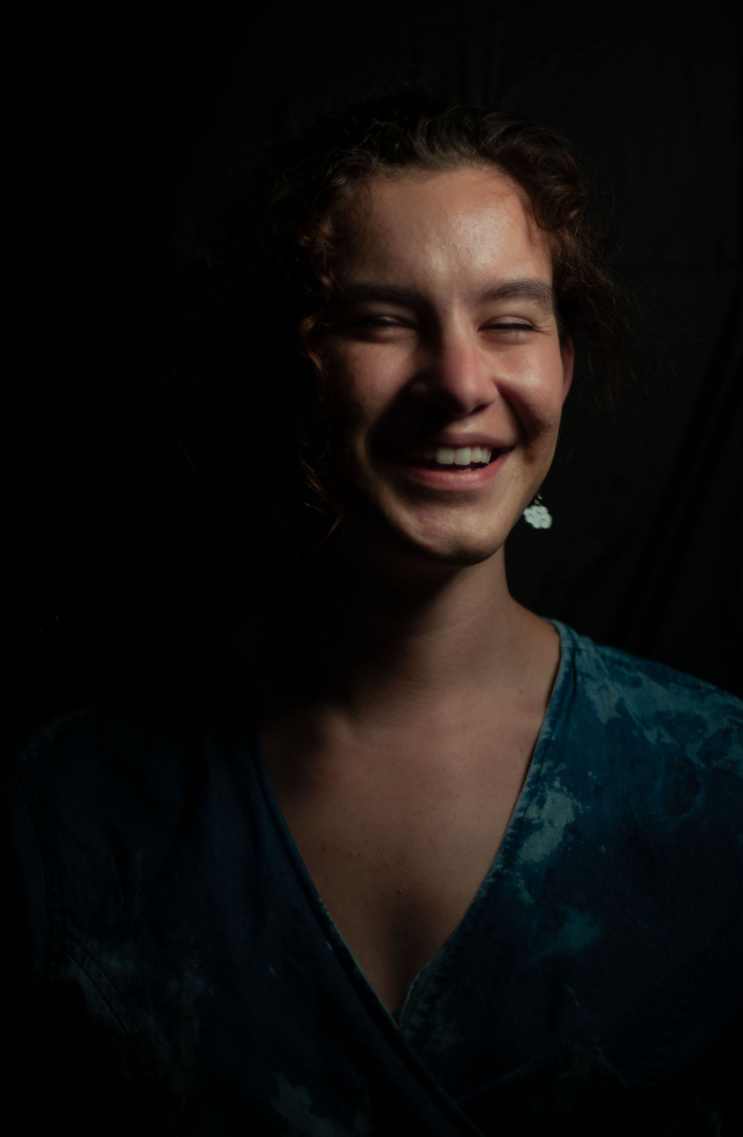 Portrait of a woman highlighting her cheeks and smile in laughter against a dark background