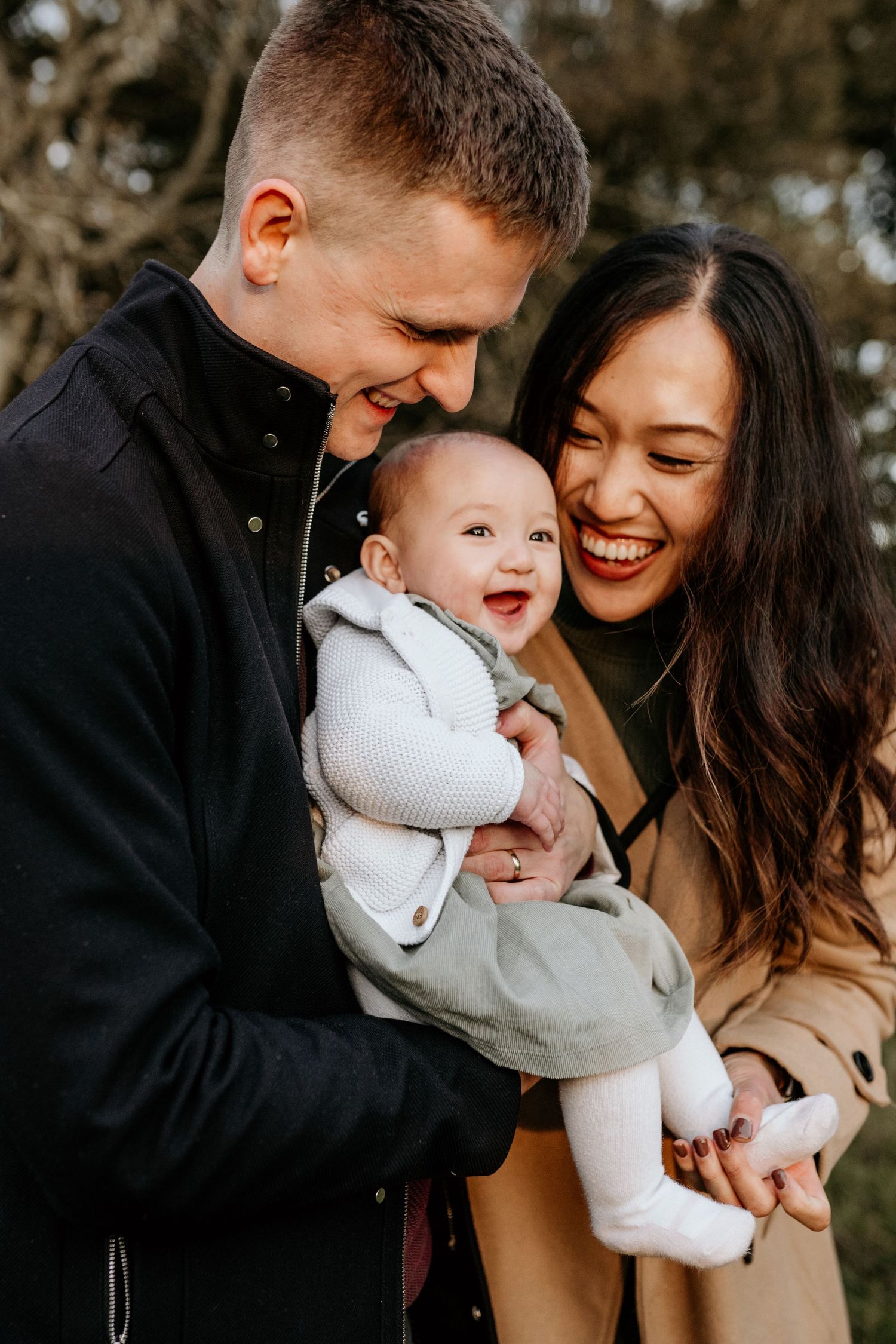 Candid moment of parents laughing with their baby at sunset during a Hertfordshire family photography session