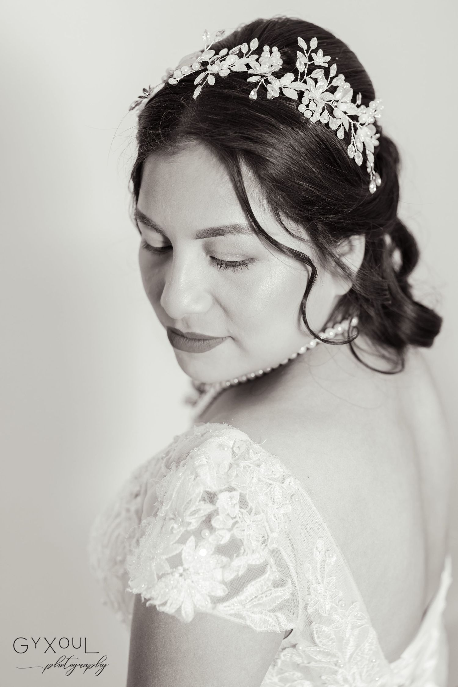 An elegant bridal portrait in black and white showcasing a delicate floral crown and lace detailing.