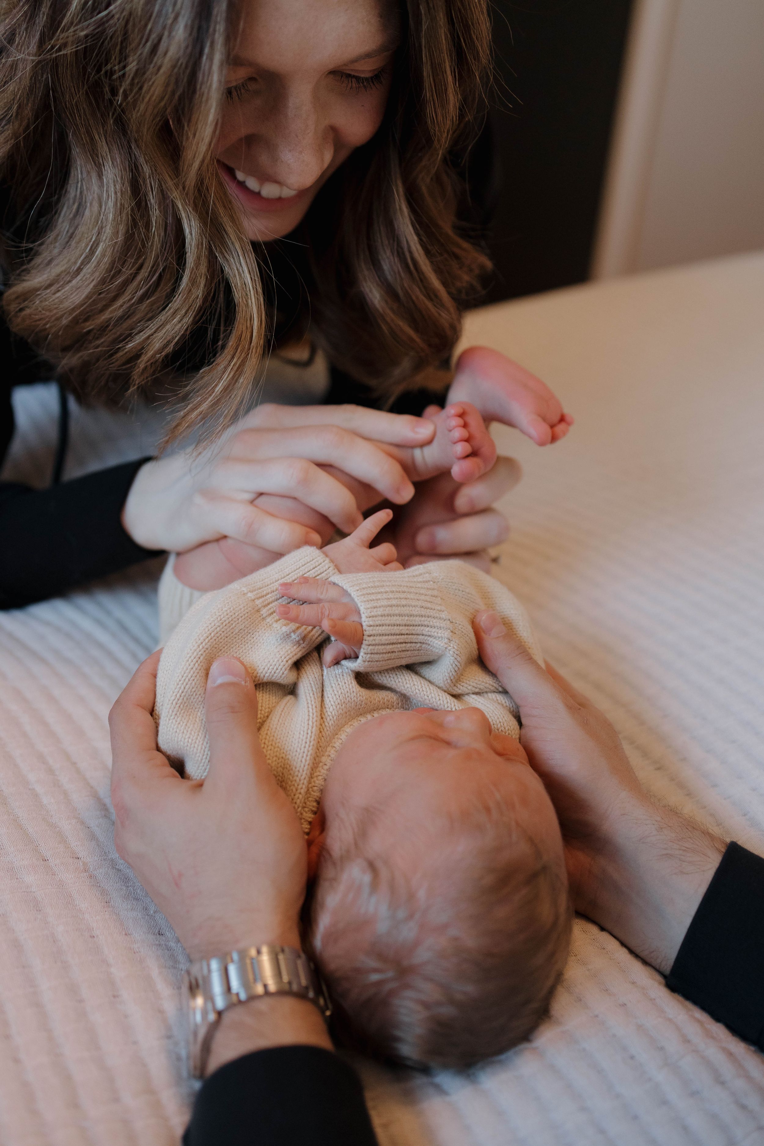 A tender moment captured as a mother plays with her baby lying on a pink blanket.