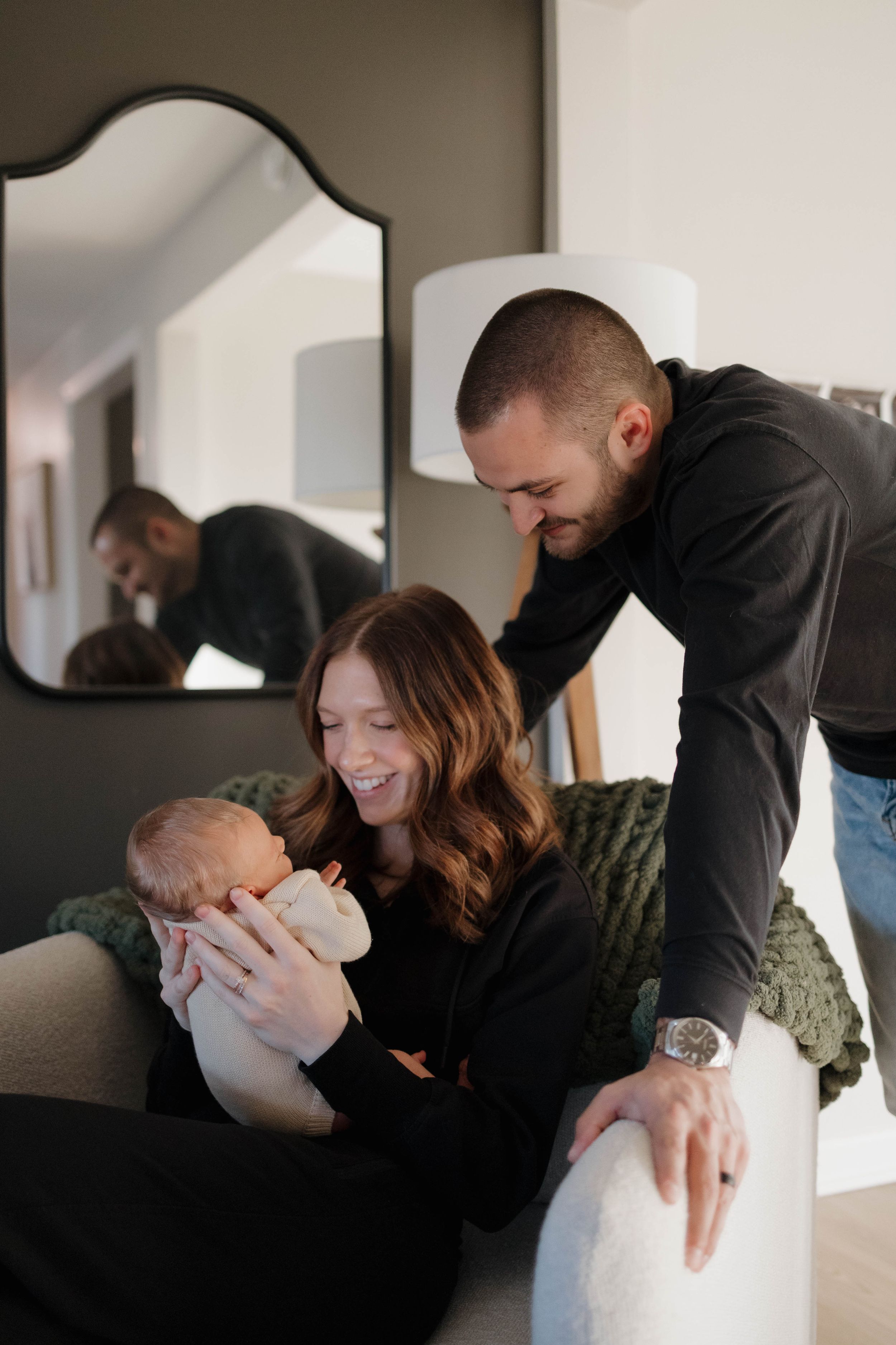 A family shares a tender moment on the couch as they lovingly gaze at their baby at home.