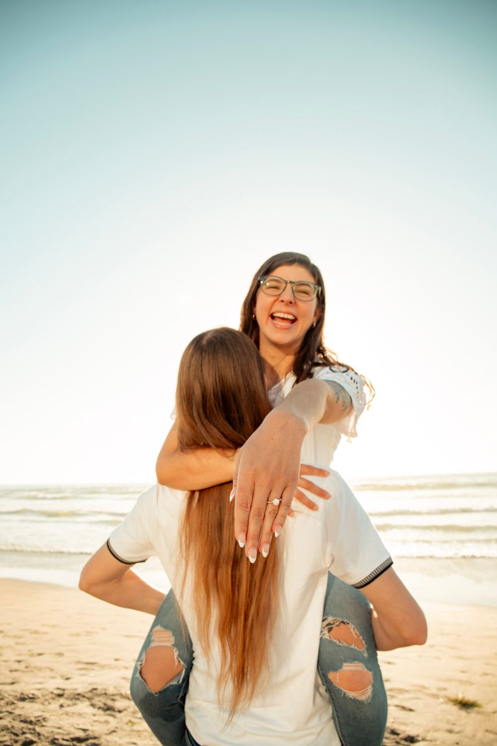 Happy couple sharing playful piggyback ride on sunny beach.