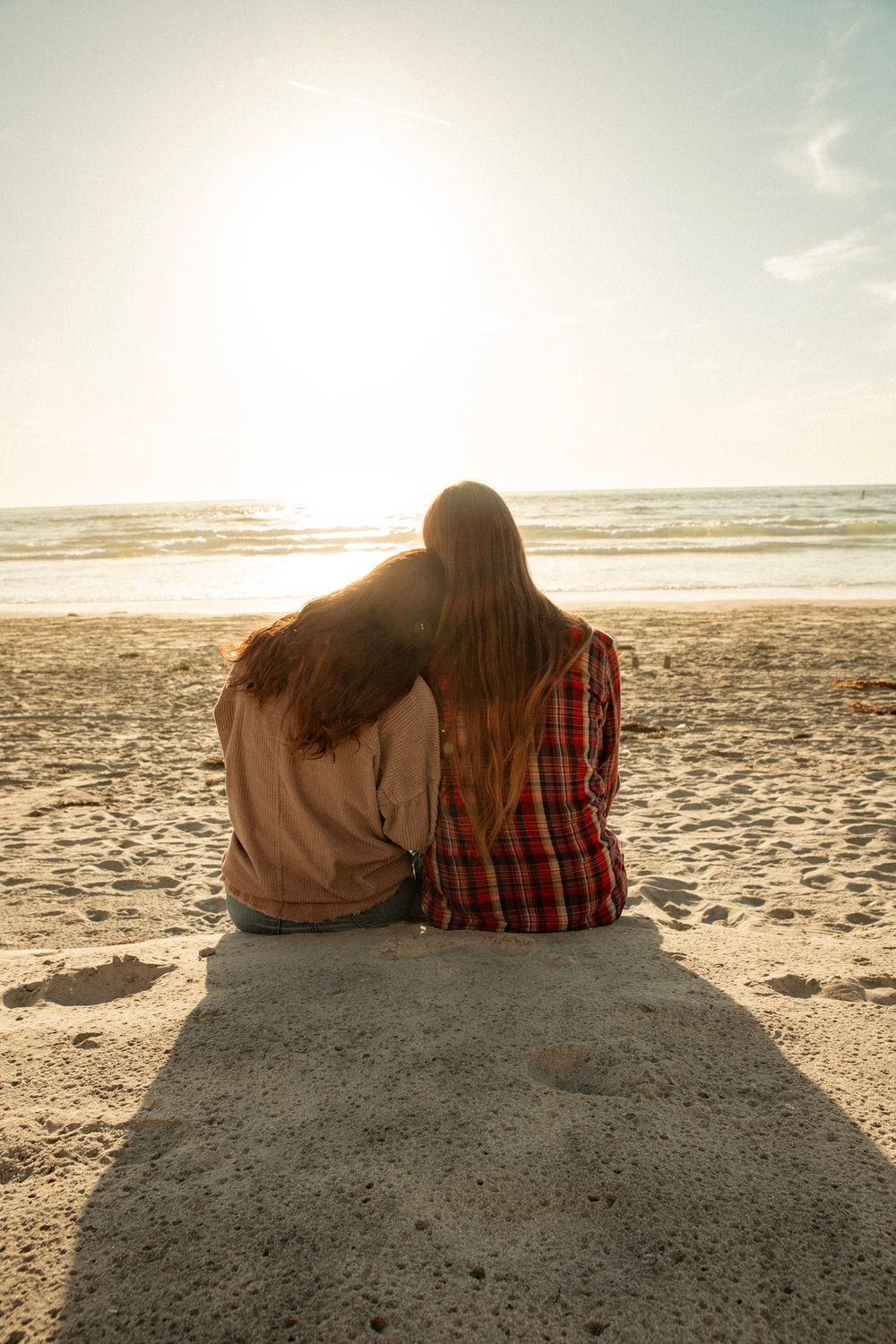 Couple sitting together watching sunset on concrete ledge at beach.