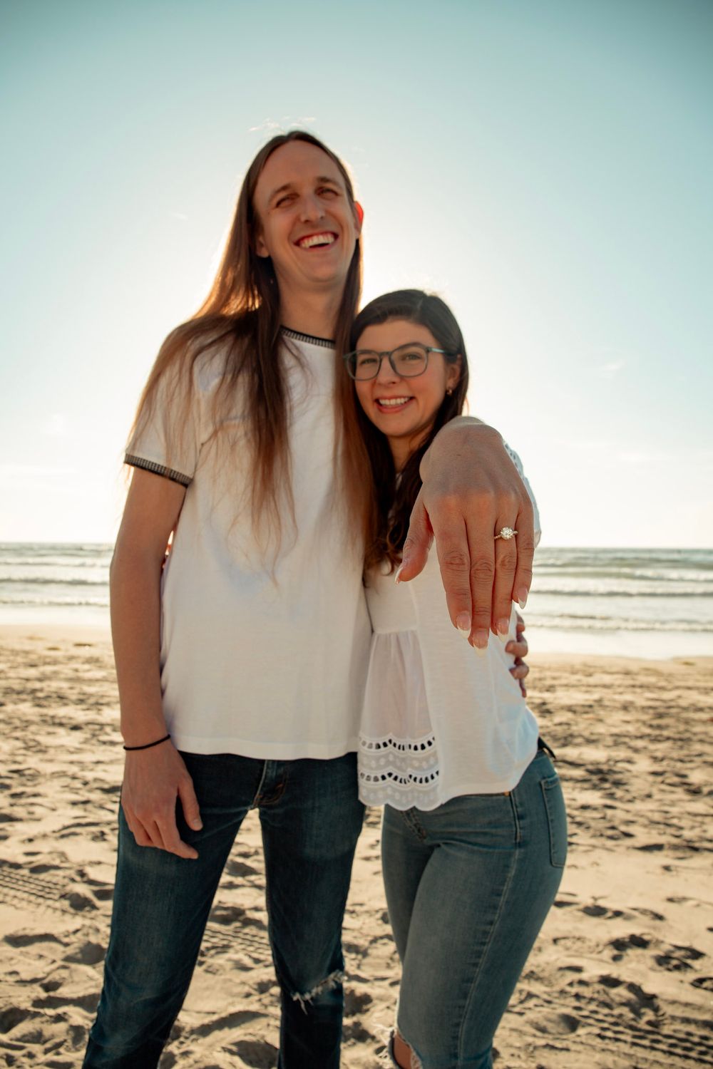 A joyful couple smiling together on a sunny beach.