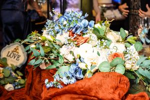Colorful wedding floral arrangements with blue hydrangeas and white roses displayed at a reception table.
