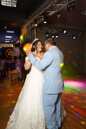 A couple shares their first dance at a wedding reception with colorful disco lights illuminating the dance floor.