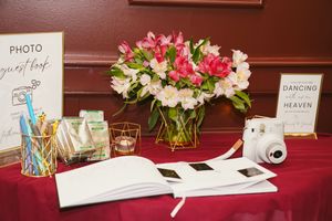 A reception table decorated with pink floral arrangements and signage for a wedding celebration.