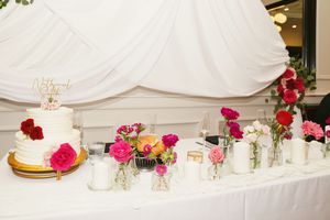 Wedding reception table settings with white linens, gold chargers, and pink floral centerpieces create an elegant atmosphere.