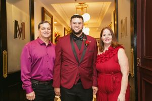Wedding party dressed in coordinating burgundy and magenta outfits posing in an elegant hallway.