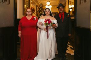 A wedding party walks through an elegantly lit hallway during an indoor celebration.