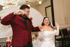 Newlywed couple shares joyful laughter in a burgundy and white wedding celebration.