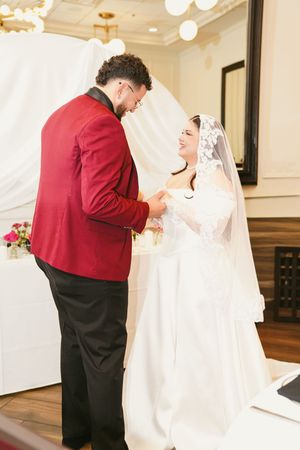 A wedding couple shares an intimate moment during their ceremony in an elegant indoor venue.