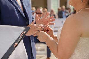Close up view of bride and groom exchanging wedding rings during wedding ceremony at indoor venue.