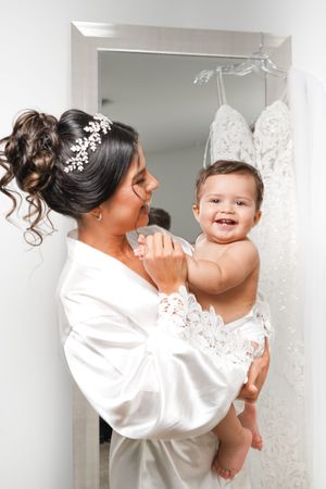 A series of tender moments between a parent and baby in white clothing against a bridal shop backdrop.