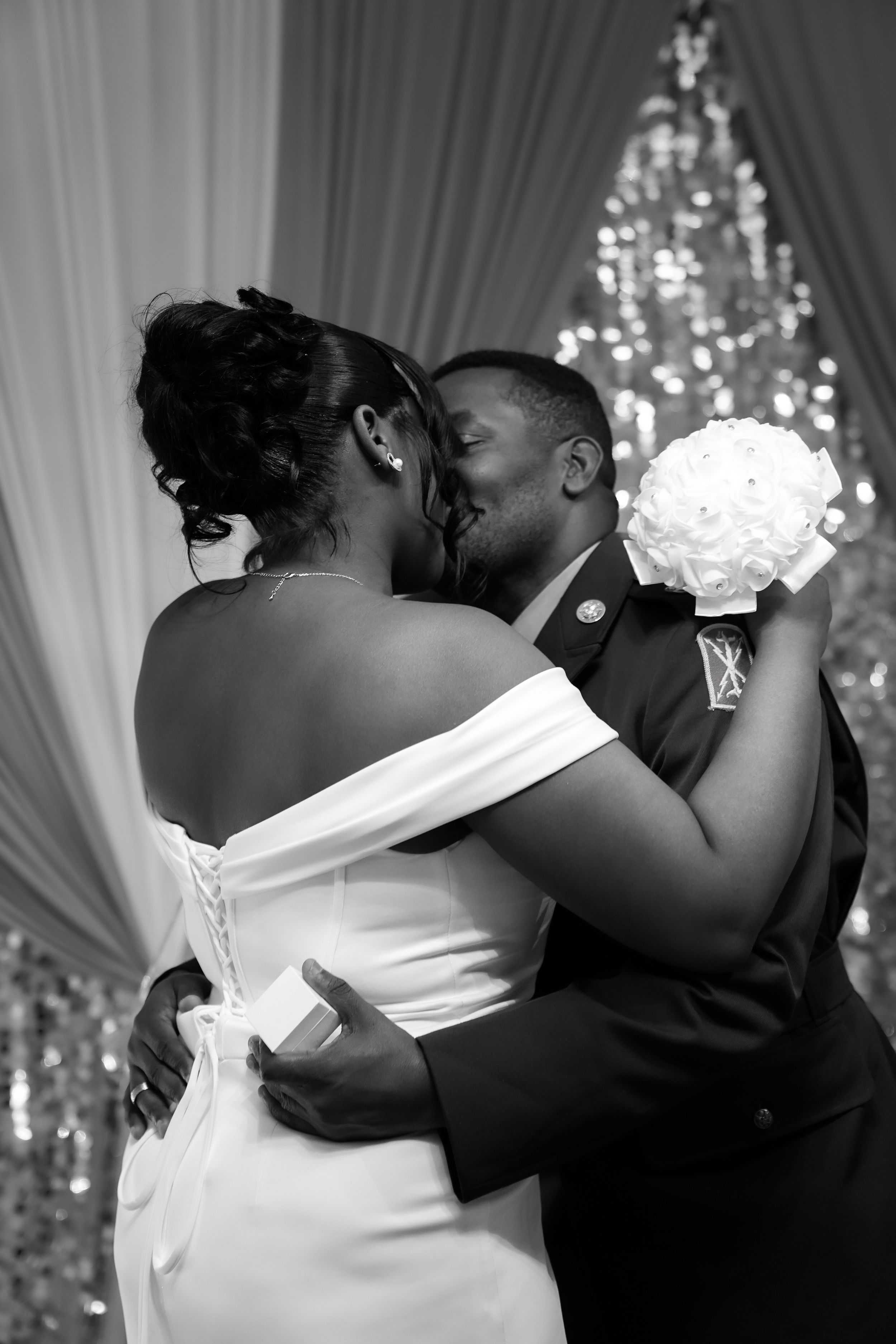 A romantic black and white sequence of a newlywed couple sharing their first kiss at a wedding reception with chandeliers.
