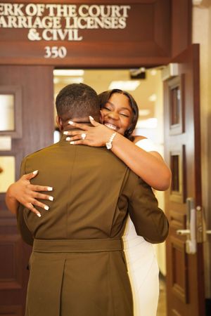 A couple shares a warm embrace in front of a marriage license office at the courthouse.
