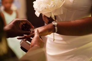 A close-up view of hands adjusting a white wedding dress with delicate fabric and intricate details.