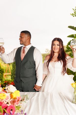 A couple shares a romantic moment during their outdoor garden wedding celebration with colorful flowers in the background.