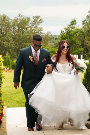 Wedding party in sunglasses walking through outdoor venue on sunny day.