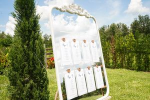 White lawn target practice setup with paper targets stands against lush green summer field and forest backdrop.