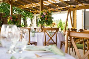 White tulle fabric decorates a rustic wooden pergola with elegant lighting for an outdoor wedding reception setup.