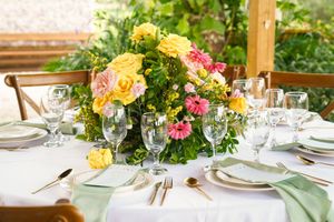 Elegant table settings with colorful floral centerpieces featuring pink and yellow flowers for an upscale garden event.