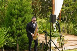 Outdoor garden wedding ceremony setup with wooden gazebo and chairs in natural setting.