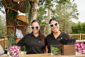 Wedding party members wearing sunglasses and dark attire pose at outdoor venue.