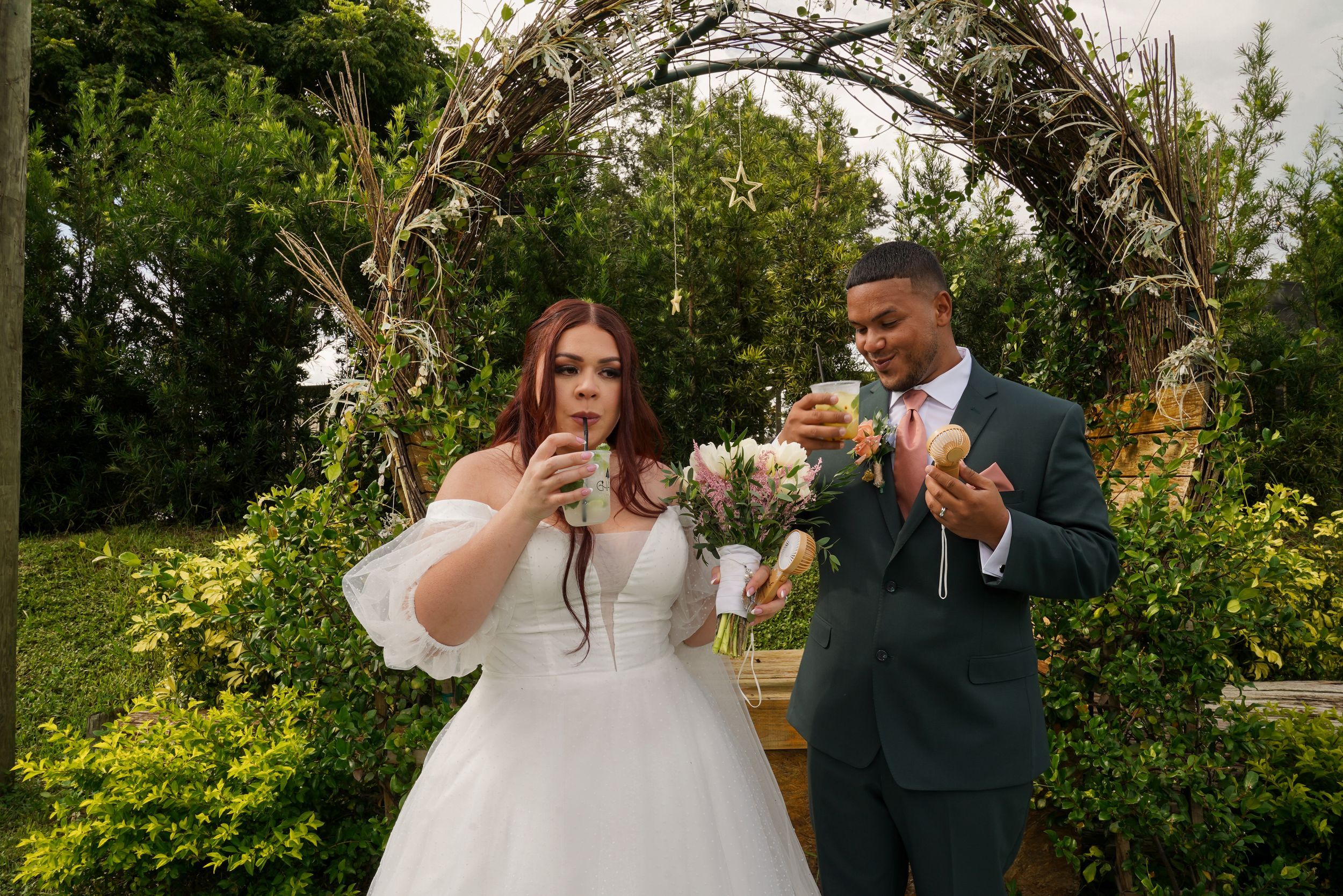 A happy couple raises their champagne glasses in a celebratory toast during their outdoor garden wedding ceremony.