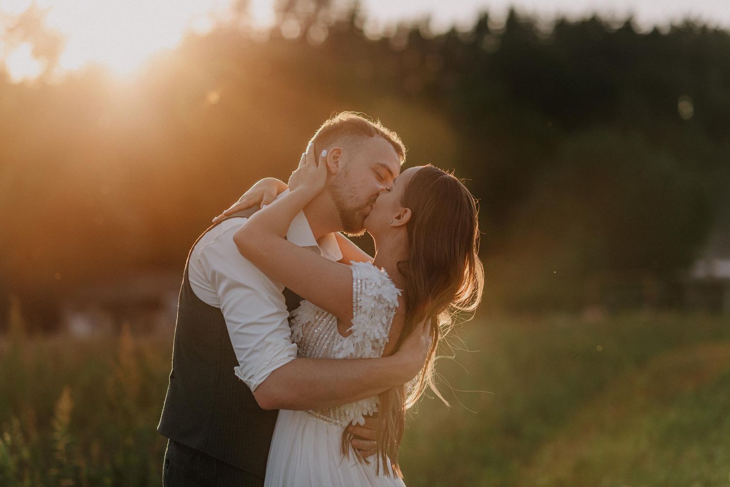 Romantic sunset photoshoot in nature with warm golden light filtering through grass and trees.