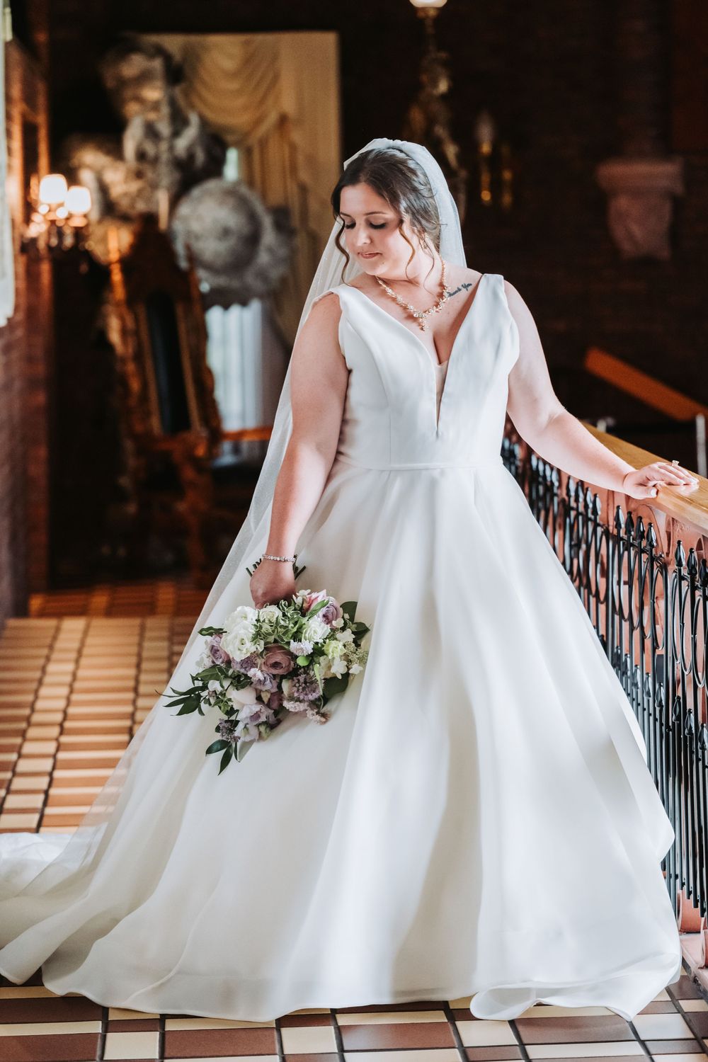 A bride in a classic white ballgown wedding dress descends a grand staircase in an elegant venue.