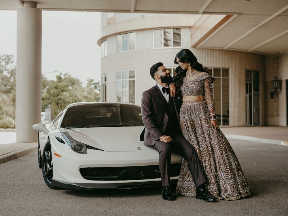 Stylish couple in formal attire stands by a white Ferrari during a wedding photoshoot.