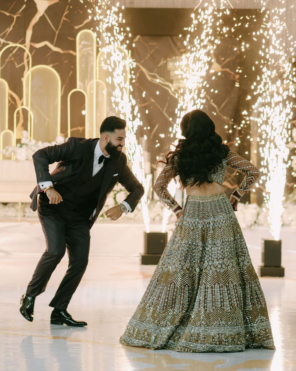 A couple dancing and celebrating against a backdrop of sparkling fireworks and illuminated arches.
