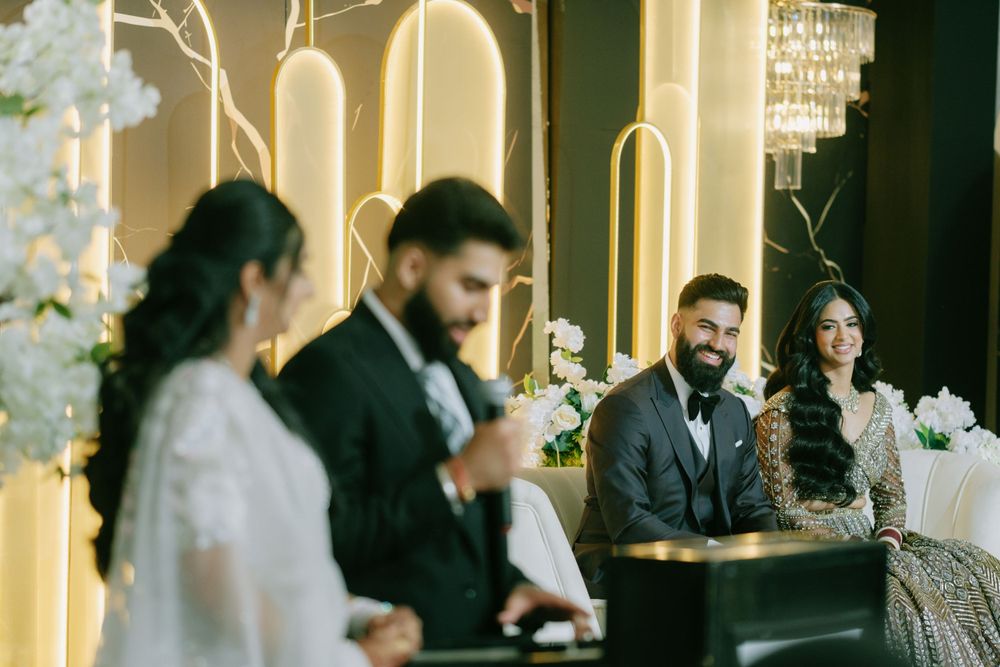 An elegant wedding reception scene with decorative arches and crystal chandeliers in warm lighting.