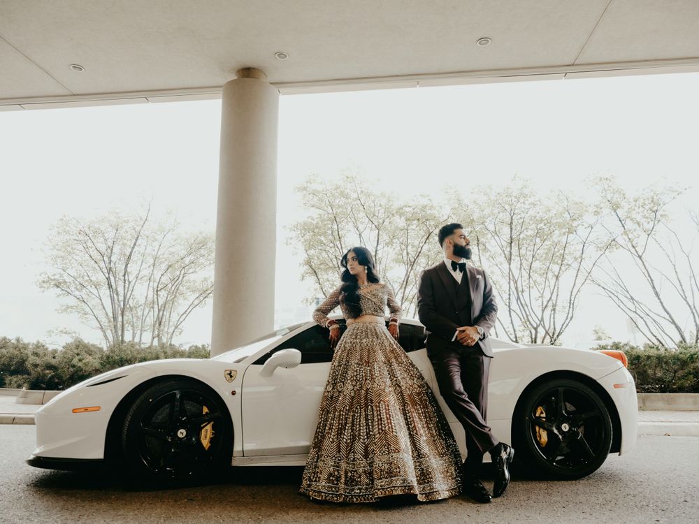 A white sports car parked under an overhang with people in formal attire posing next to it.