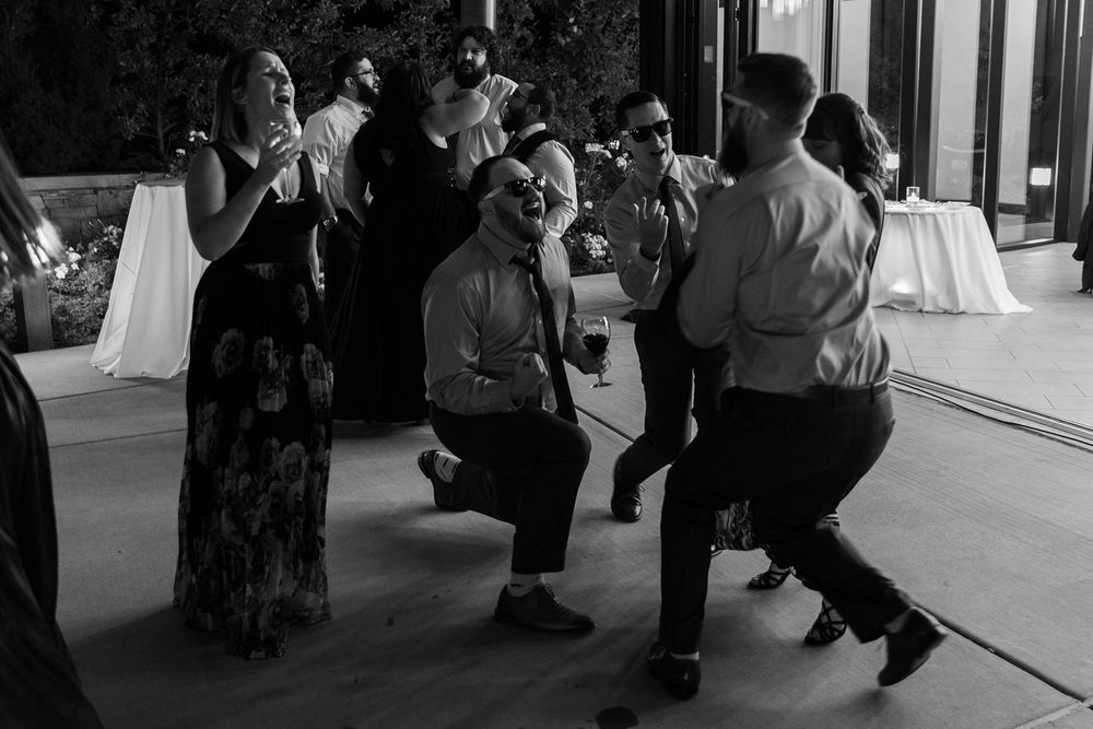 Wedding reception guests dance and celebrate in black and white on a dance floor at an evening event.