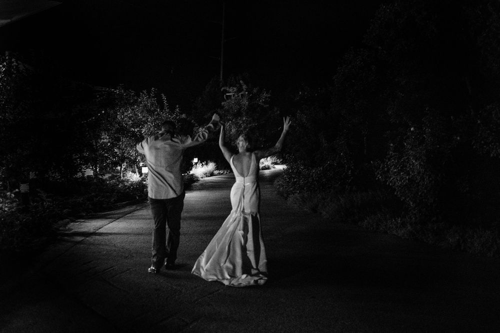 A couple dances together on an illuminated pathway at night, creating a romantic black and white scene.