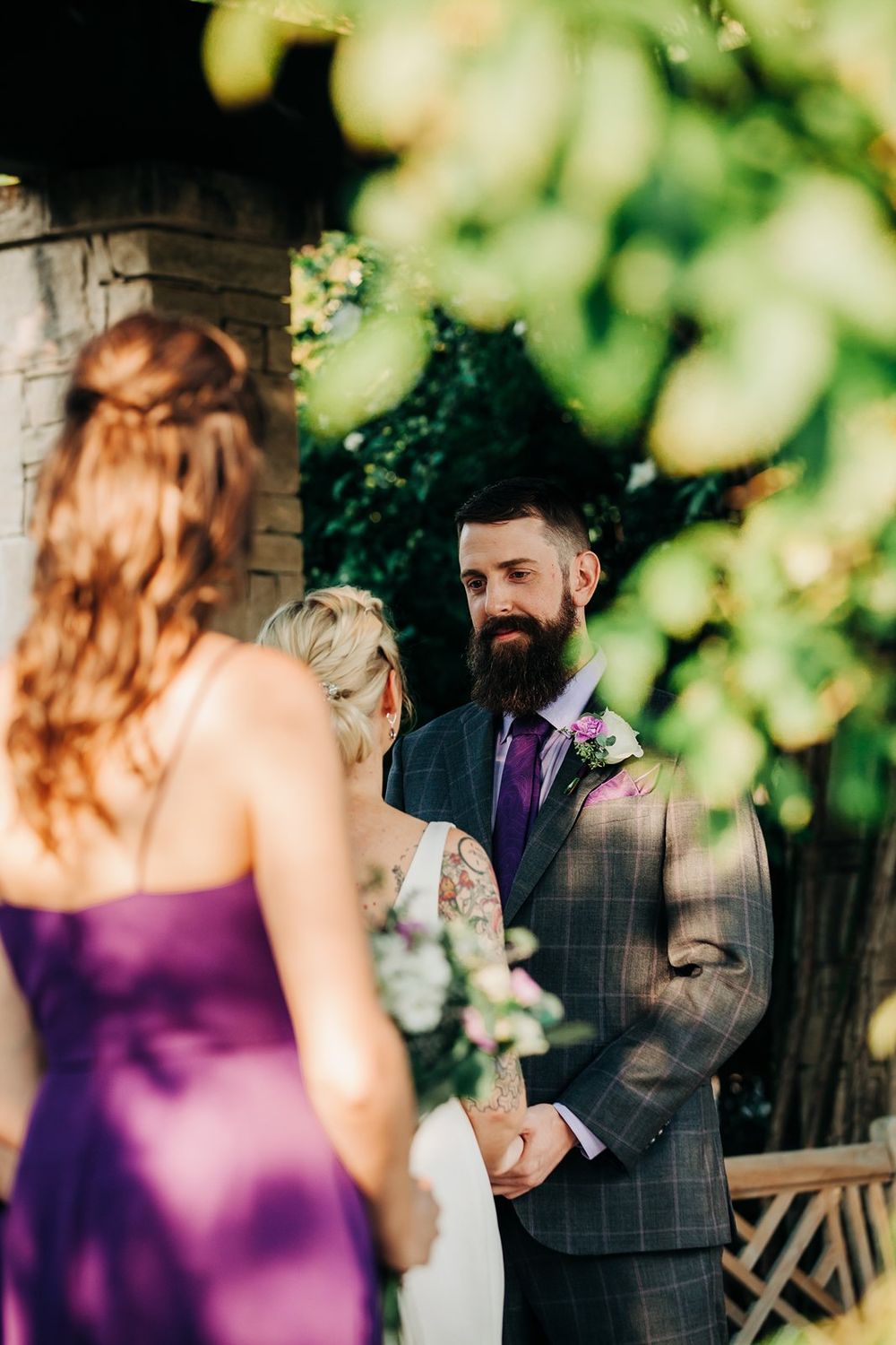 Wedding ceremony with couple standing under floral archway in garden setting.