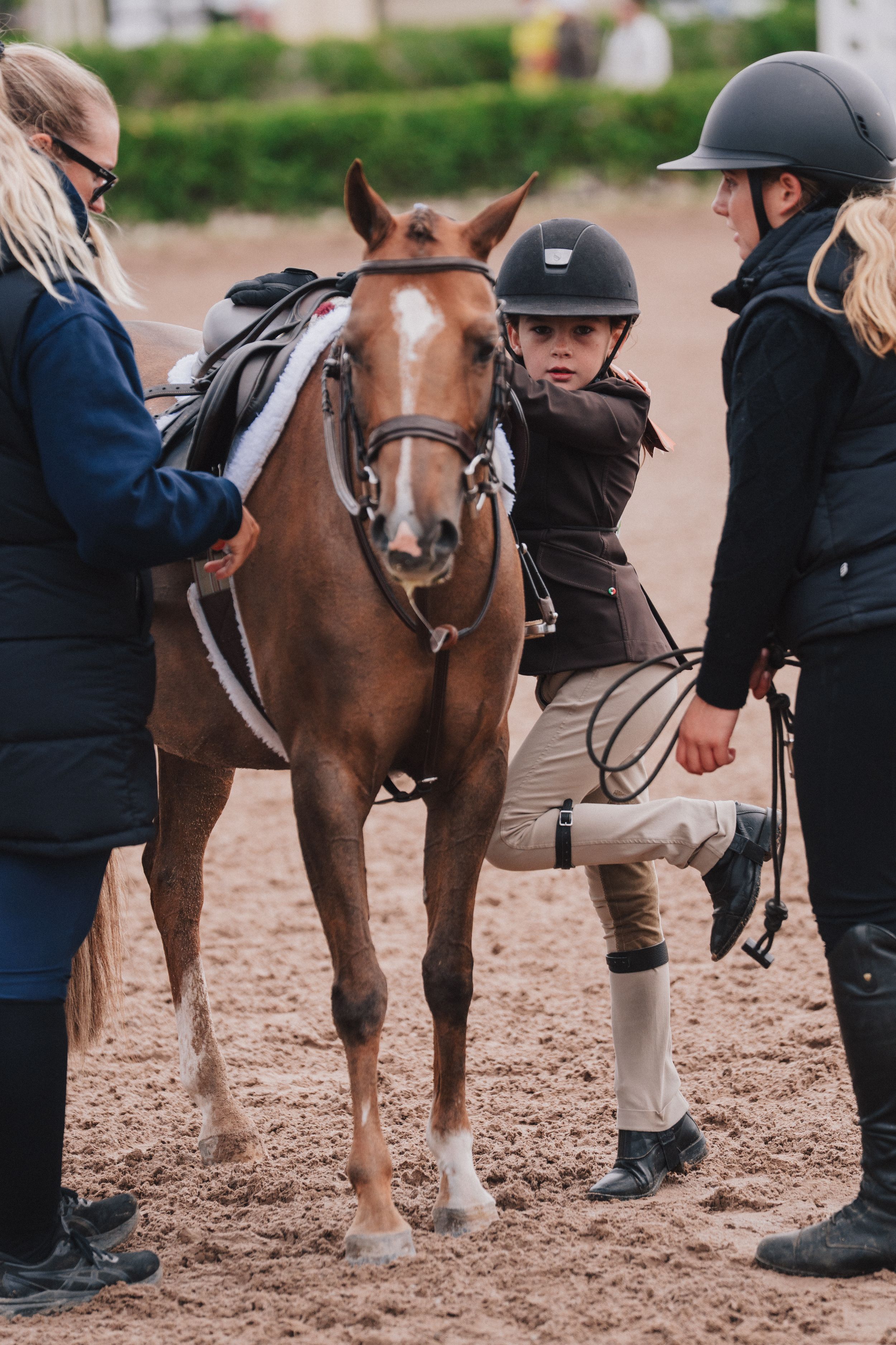 Horseback riding instructor shows correct riding posture and positioning techniques during an equestrian lesson.