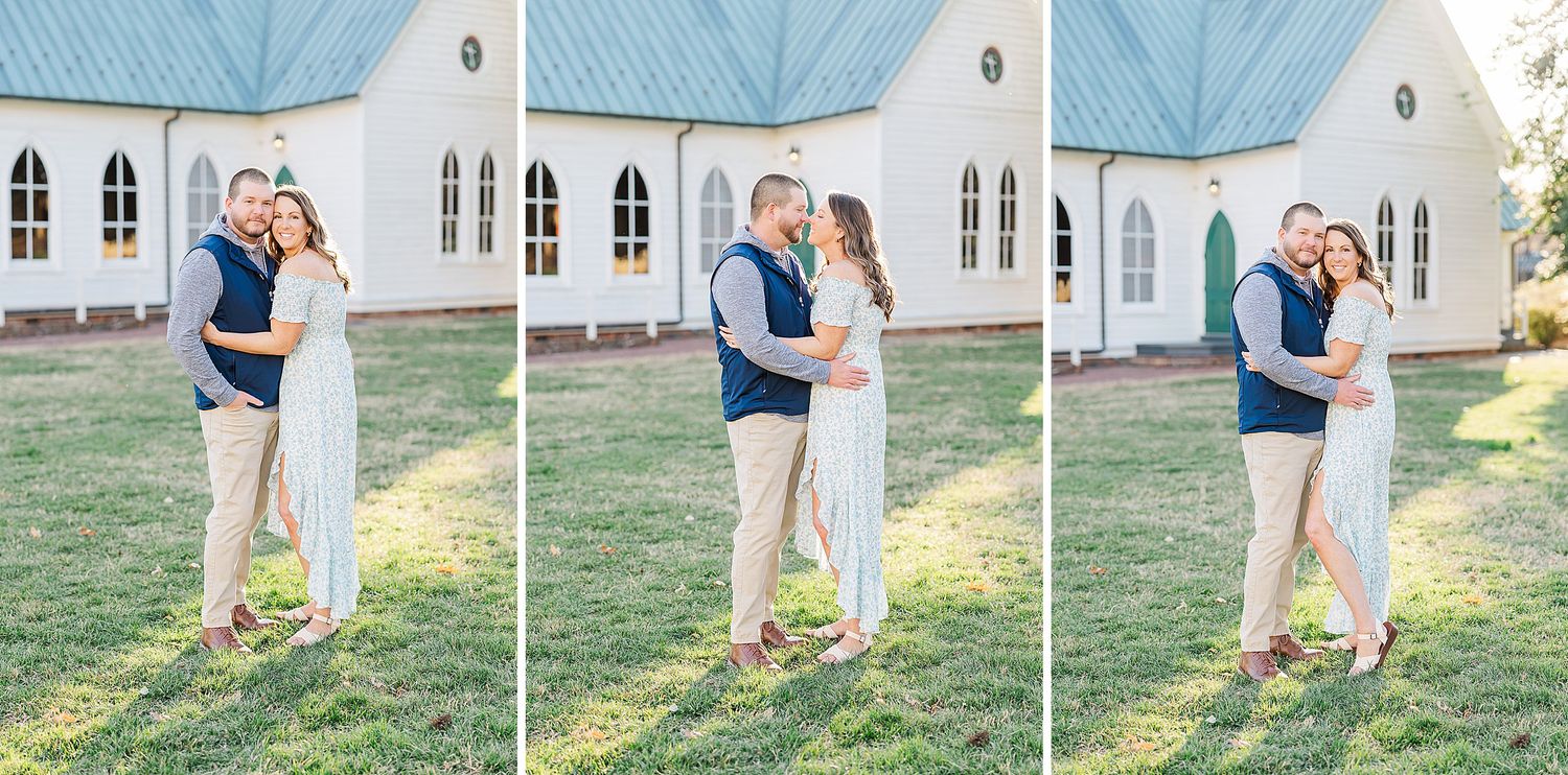 A romantic couple embraces outdoors on a sunny day with a beautiful white church building in the background.