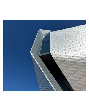 Olympic and Paralympic Museum angular white architectural detail against bright blue sky showing textured facade pattern.
