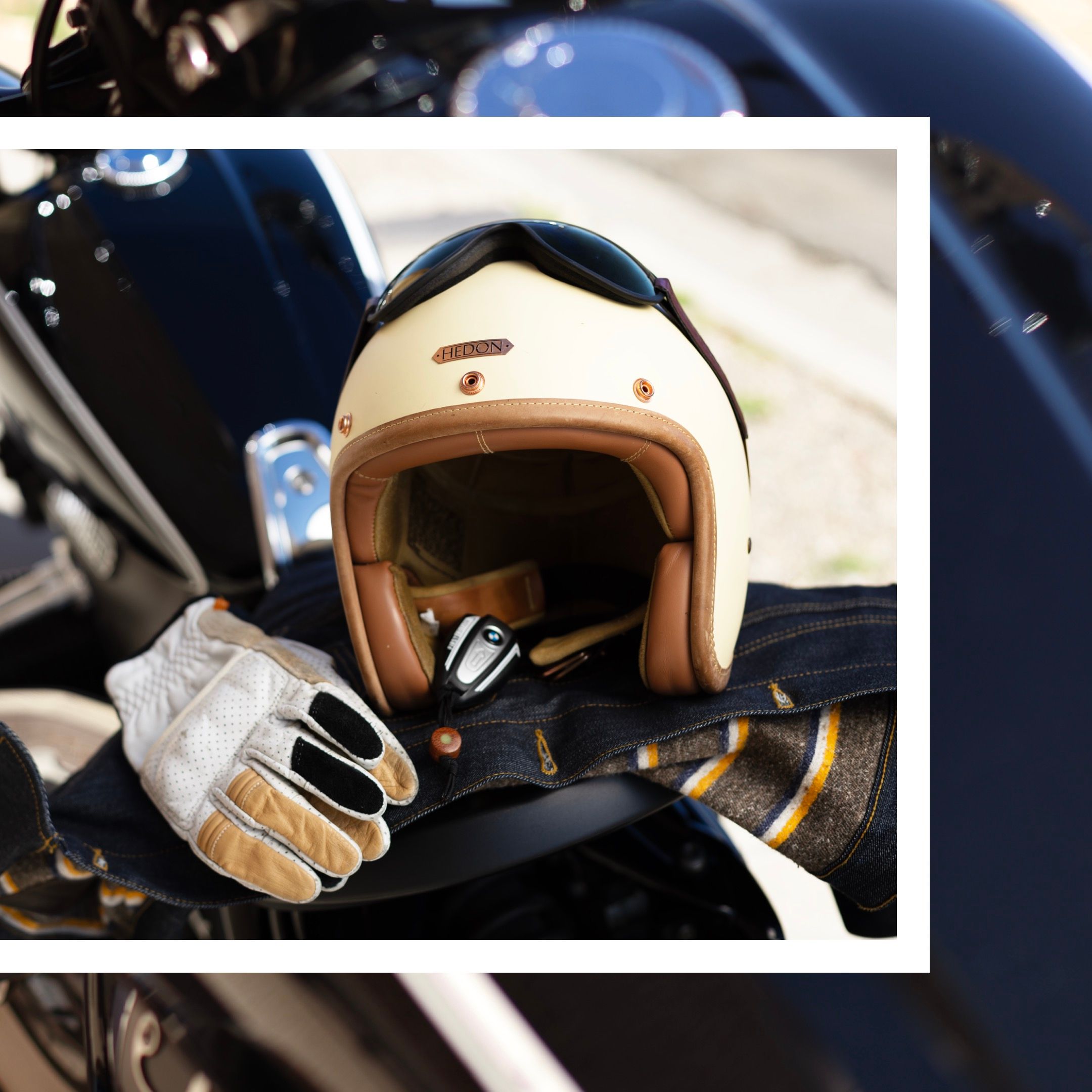 A vintage-style cream motorcycle helmet and gloves on a dark motorcycle seat.