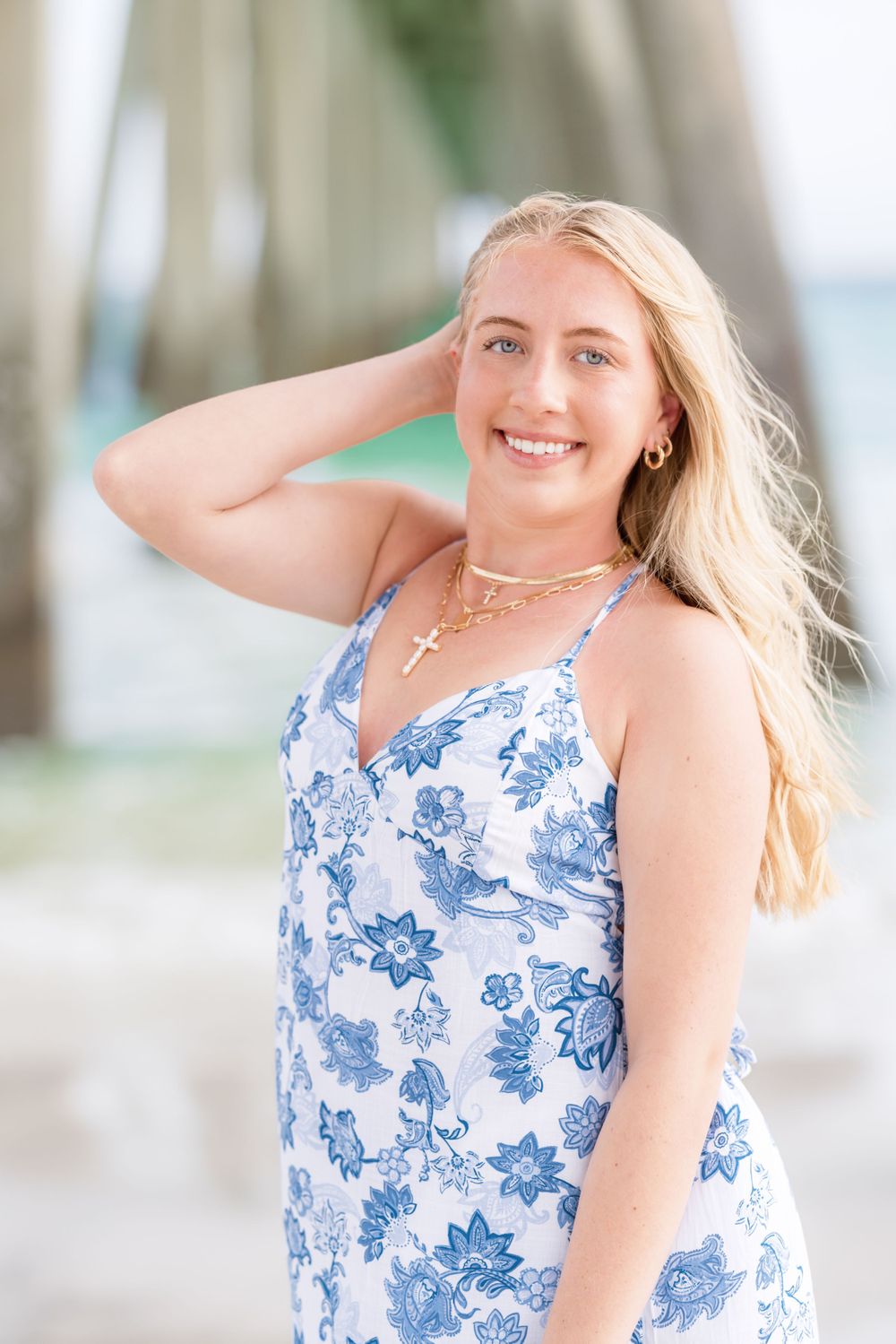 Woman in a blue and white floral sundress poses outdoors with long blonde hair on a summer day.