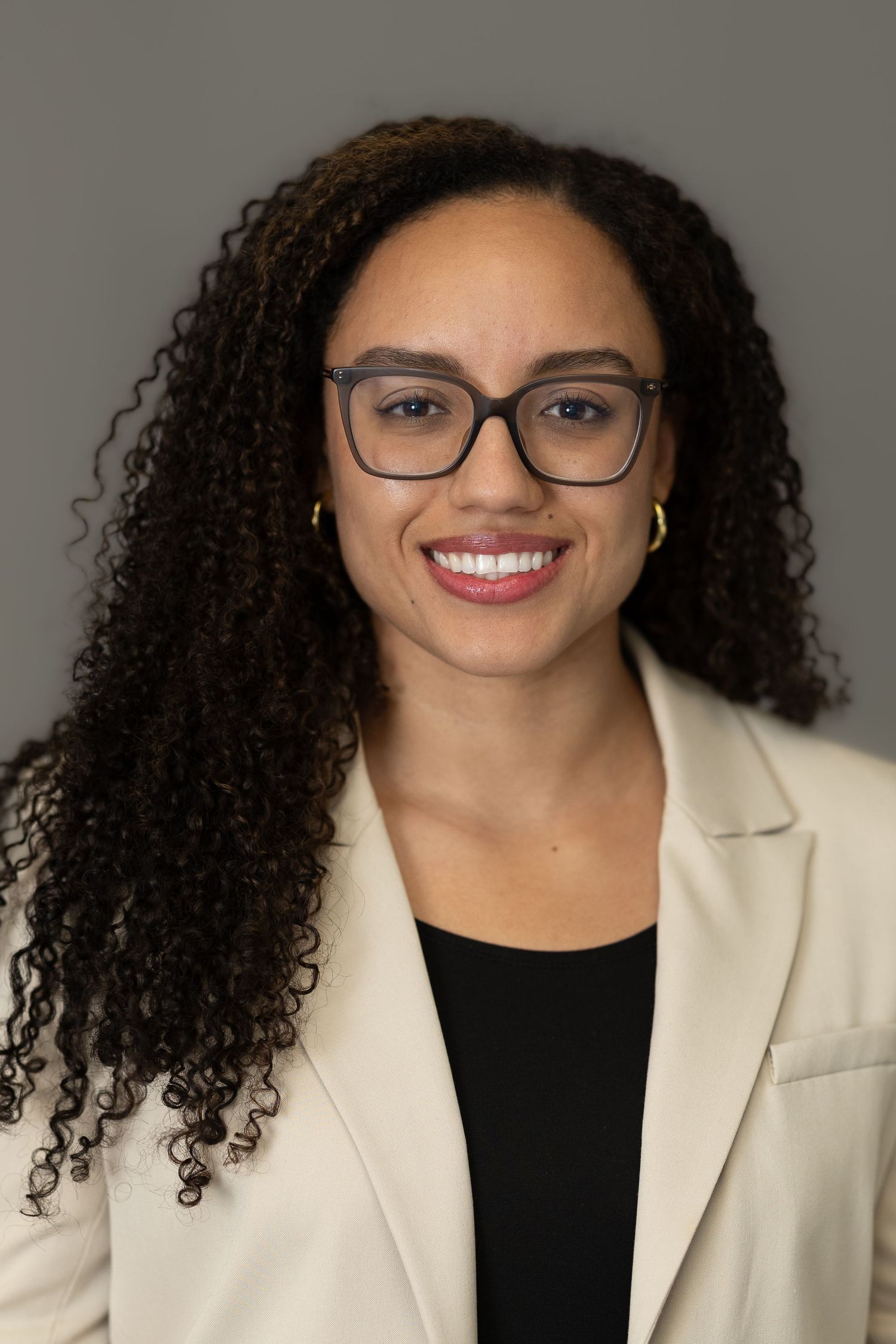 Professional headshot series showing bright smile and curly hair against neutral background wearing white blazer.
