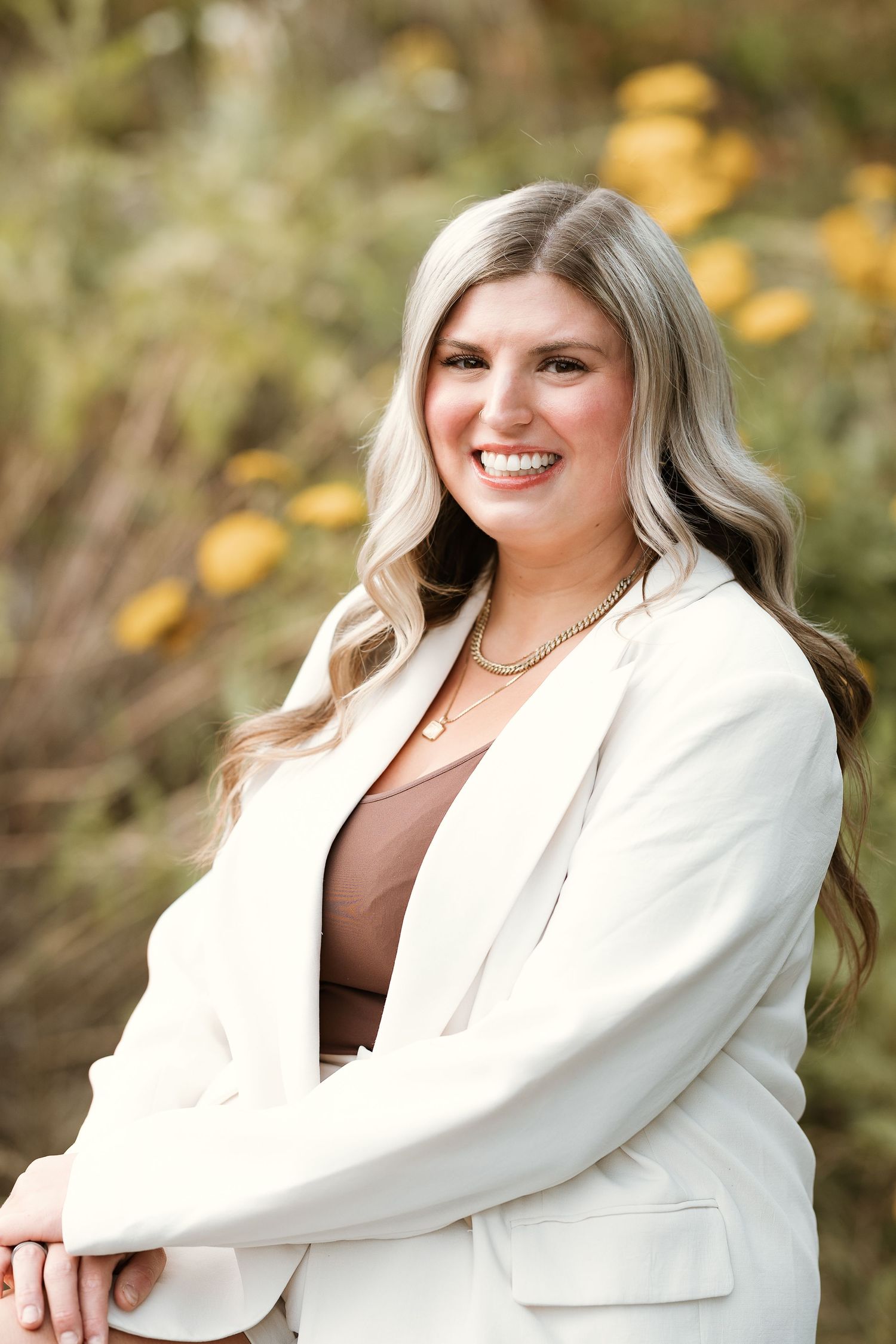 Professional outdoor portrait session featuring a white blazer against a soft autumn background with golden bokeh.