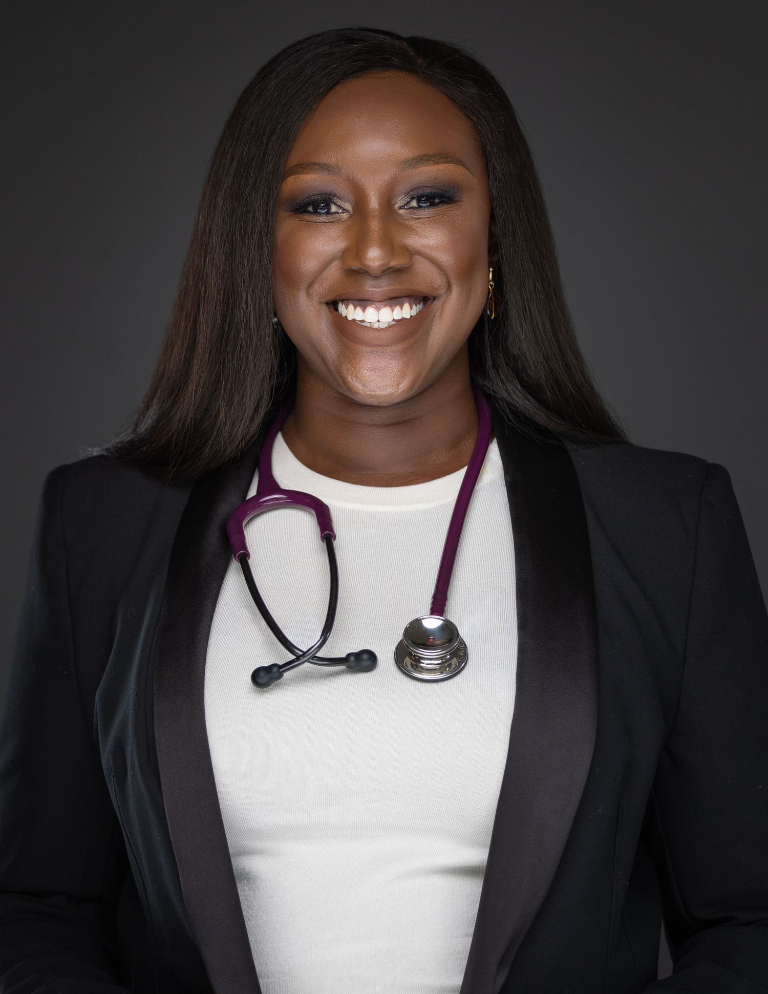 Professional portrait showing a person in a black blazer wearing a dramatic white statement necklace against a dark background.