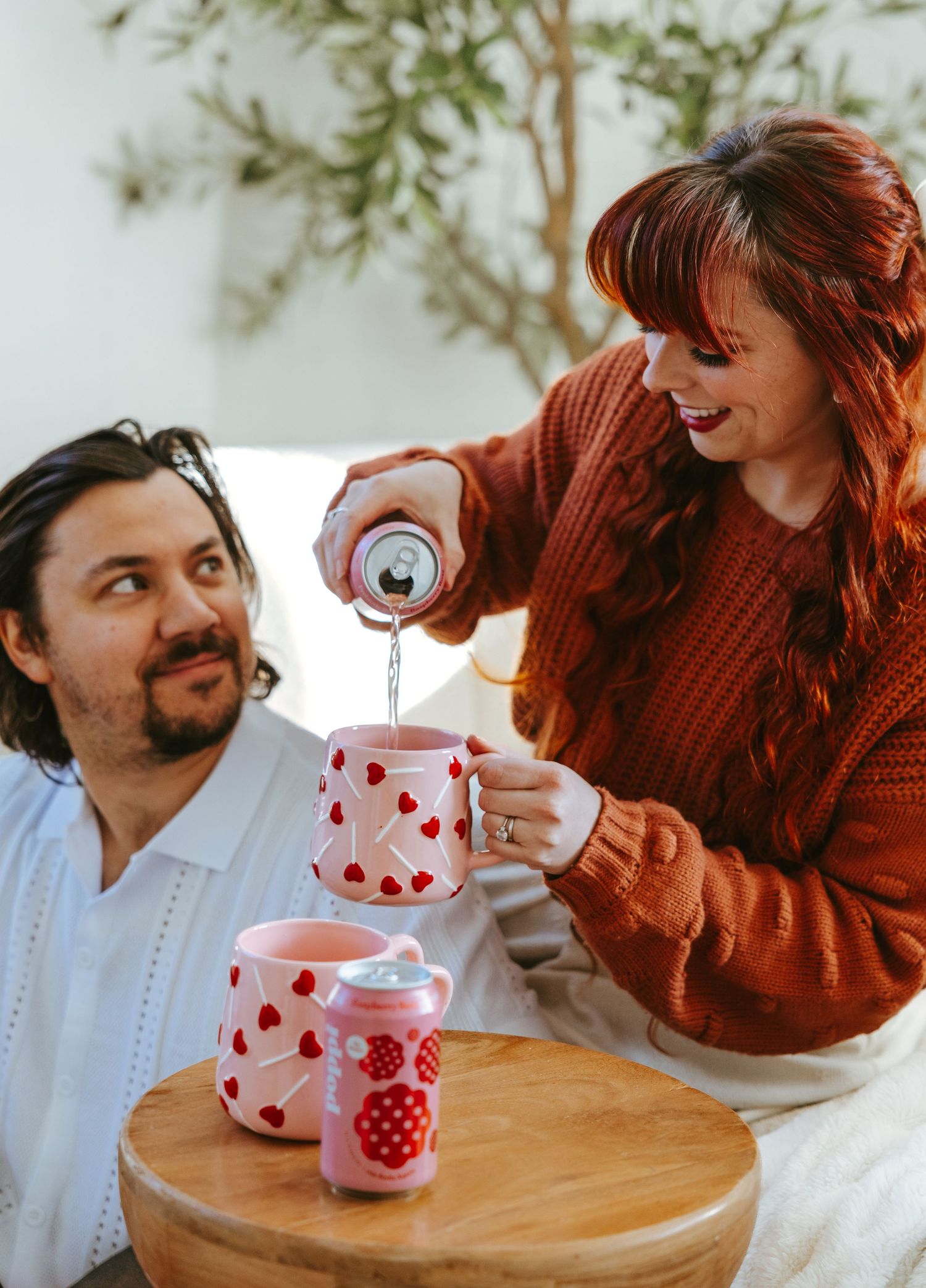 A couple shares a moment while pouring beverages into heart-patterned mugs.