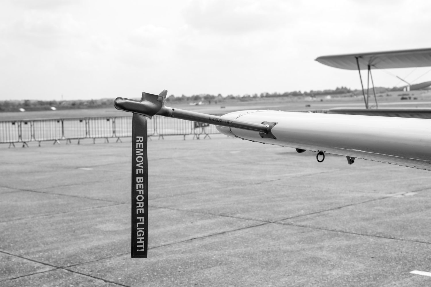 Vintage black and white photo showing aircraft wing and directional wind speed indicator pole at an airfield.
