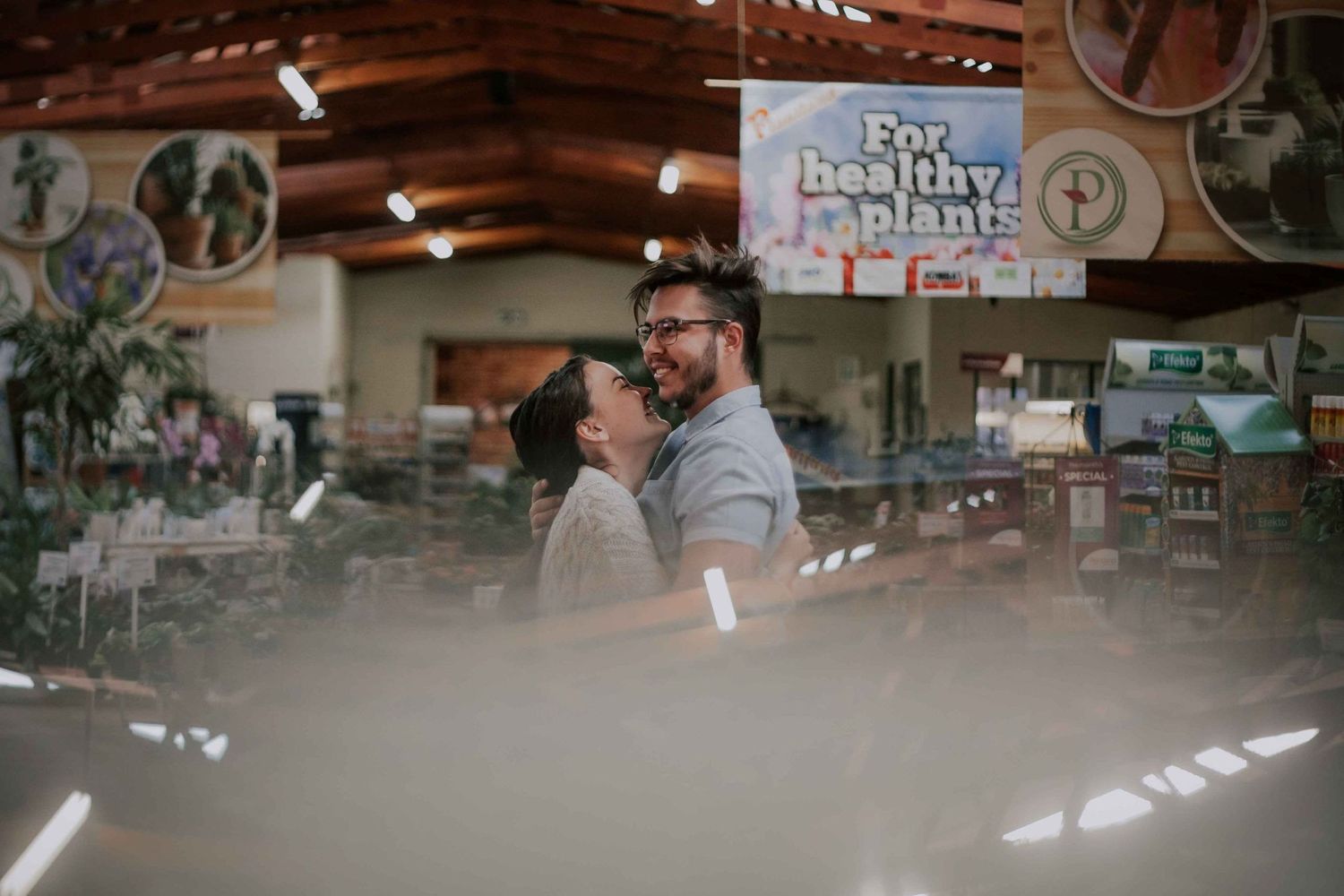 A couple shares an intimate moment in a rustic indoor setting with string lights overhead.