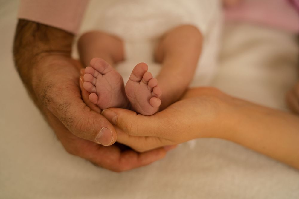 photo des pieds de bébé avec les mains de papa et maman